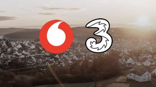 The Vodafone and Three logos over a village during sunset