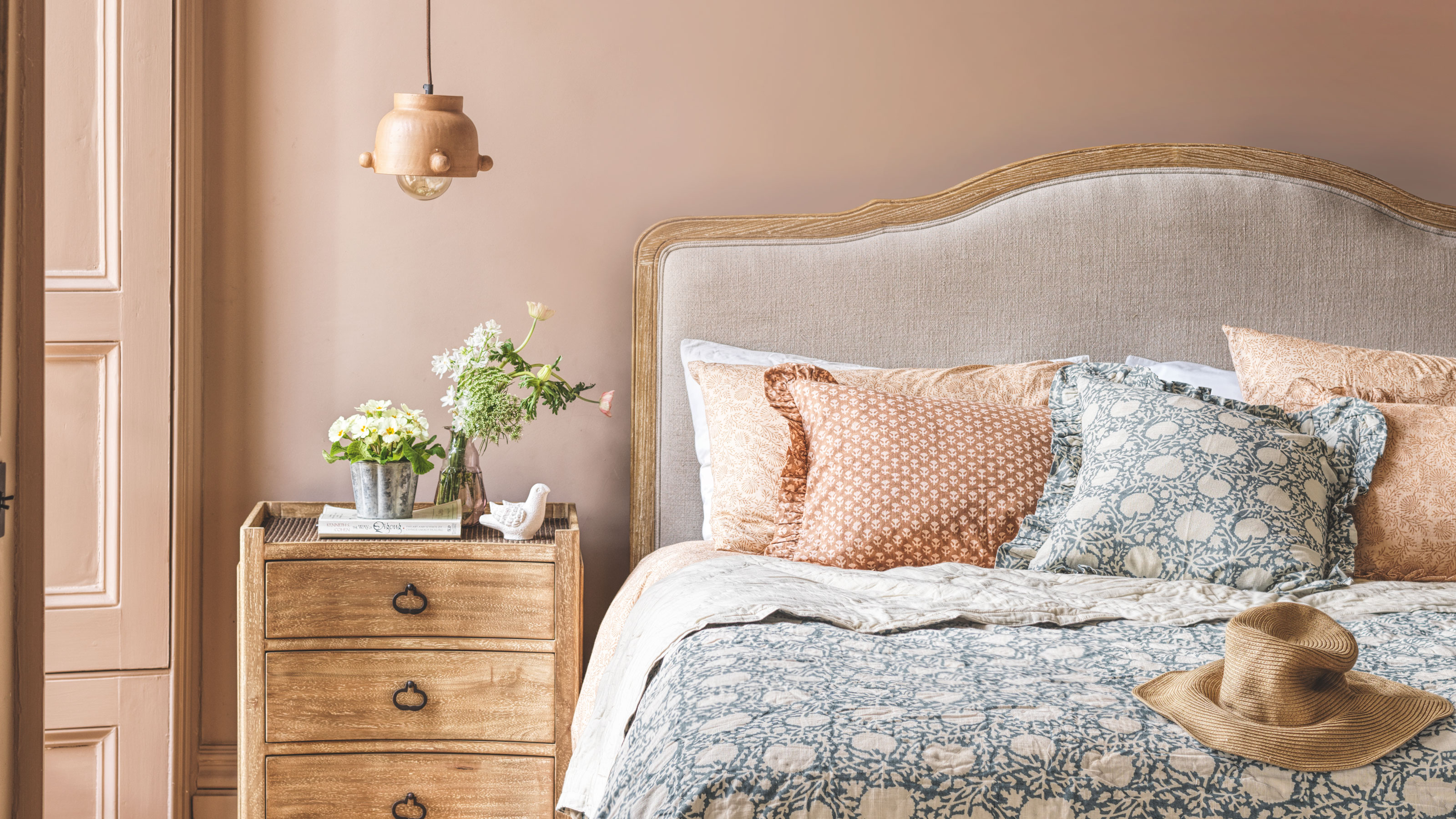 Pink bedroom with wooden bed and chest of drawers with blue pattern bedding