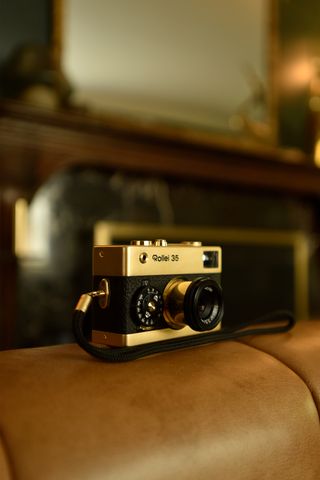 Rollei 35 Retrospekt 24K Gold Edition camera on a leather sofa in a luxury home