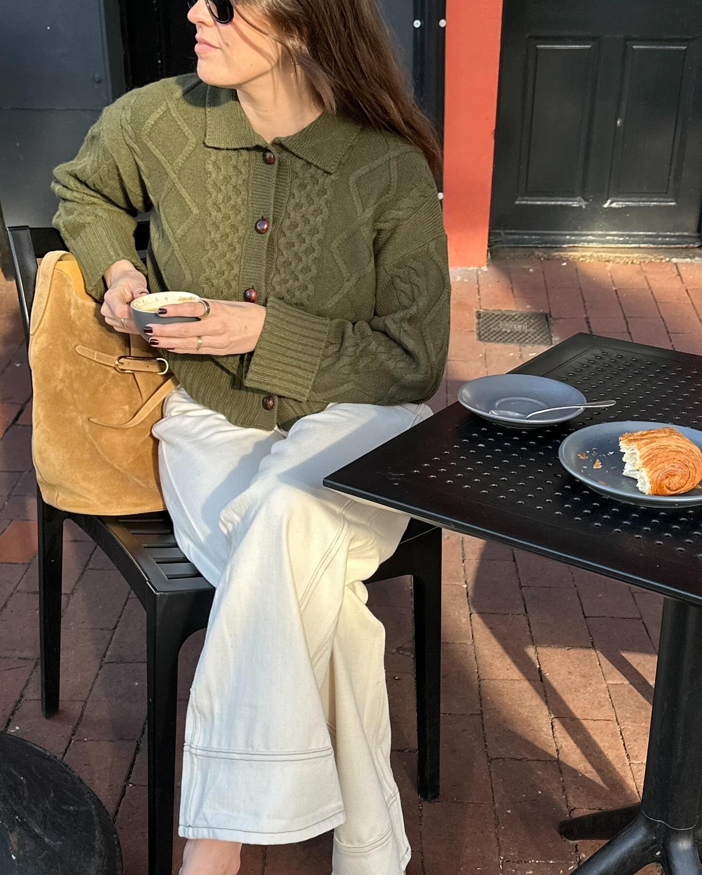 Woman wearing khaki cardigan and white jeans.
