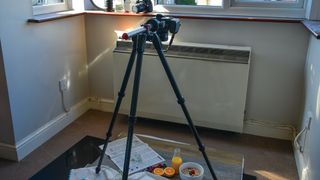 Tripod angled downwards to face flat lay beneath in bay window providing natural light