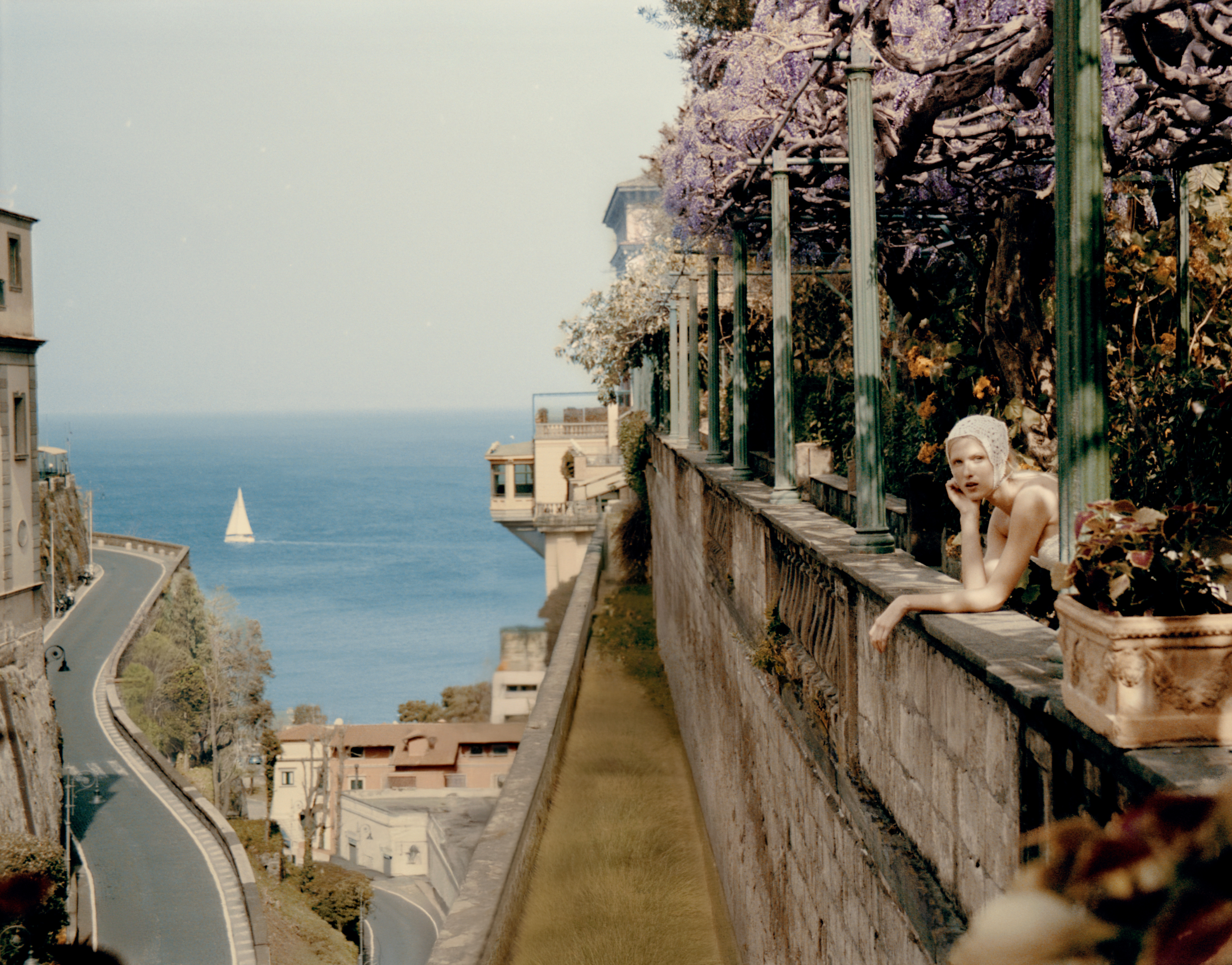 A woman wearing a headscarf leans over a balcony at Grand Hotel Excelsior Vittoria