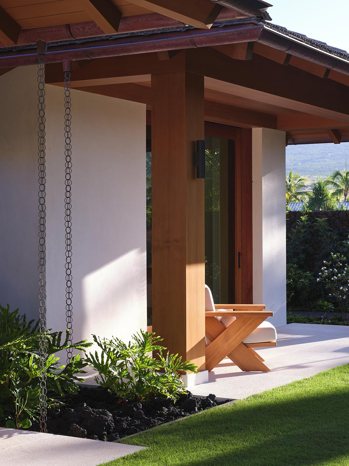 outdoor area with timber beams and rain chain with rock garden with grass and timber outdoor chair on paved patio