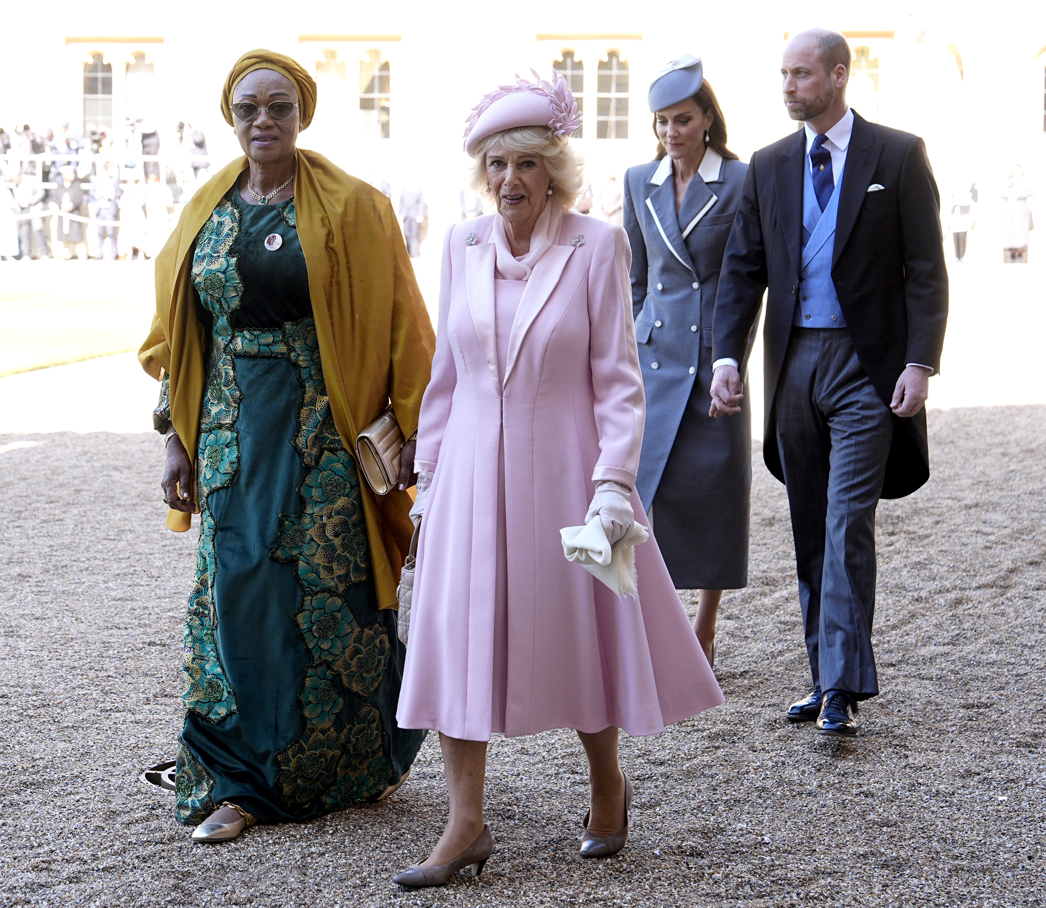 Queen Camilla in a pink coat and hat walking with the first lady of Nigeria in front of Prince William and Princess Kate