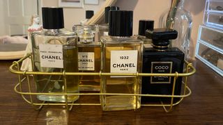 A dressing table and wire tray containing several Chanel perfumes