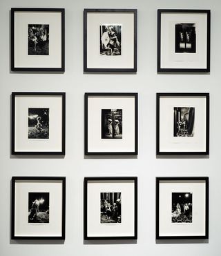 Image of a collection of black and white photos in black frames hanging on a gallery wall