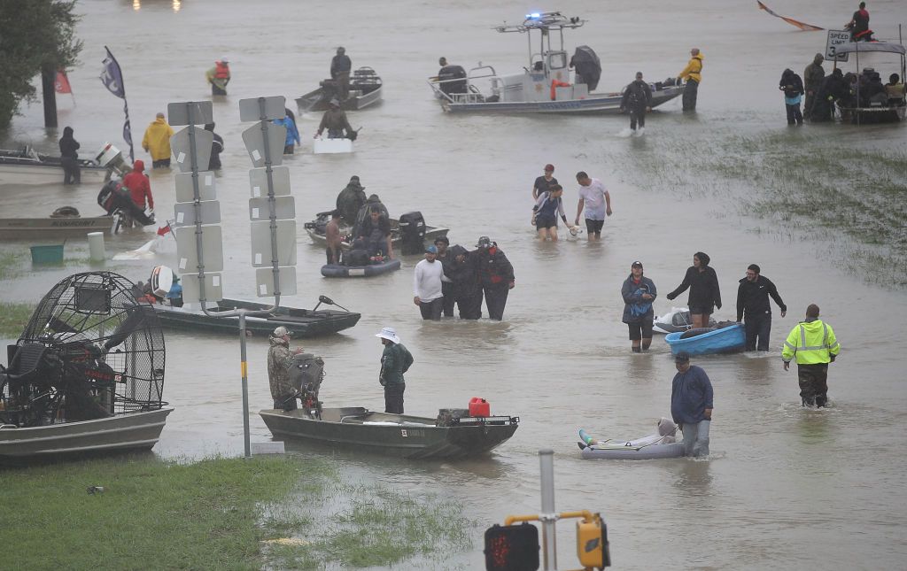 People walk down a flooded street as they evacuate their homes after parts of Houston were inundated with flooding from Hurricane Harvey on Aug. 28, 2017.