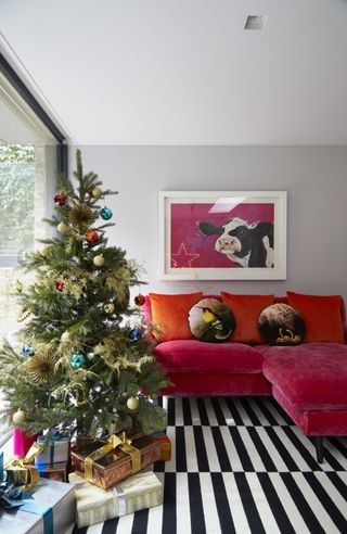 ining area detail with light grey walls, black an white striped rug and, and red velvet sofa, Christmas tree next to picture window