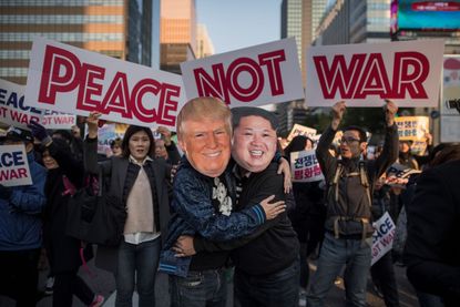 Demonstrators in Trump and Kim masks