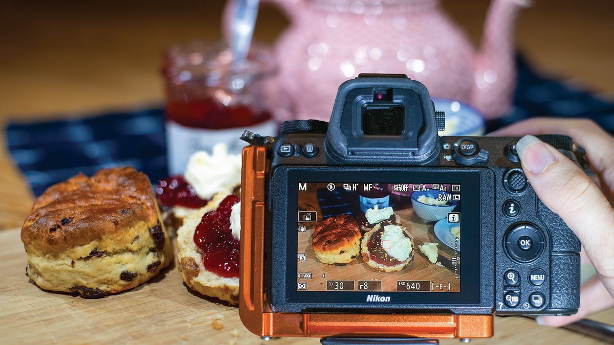 Rear LCD of Nikon Z6 II showing live view with focus peaking activated, in front of a spread of scones and jam 