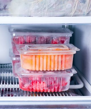 An image of a neatly organized freezer with clear plastic boxes filled with fruit including strawberries and peaches
