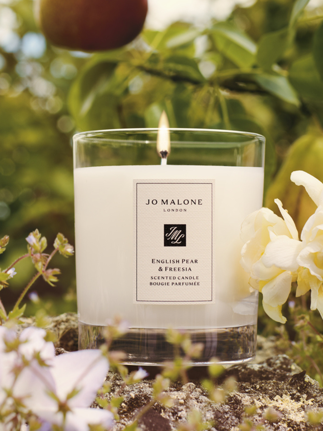 An English Pear and Freesia scented candle from Jo Malone London in a field