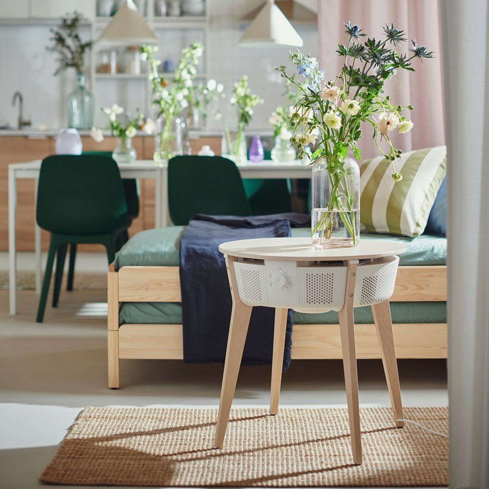 White and brown STARKVIND Table with Air Purifier with a vase of flowers on top of it, in a living room with a sofa and dining table behind it