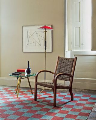 Beige living room with red and blue checked rug by Vanderhurd