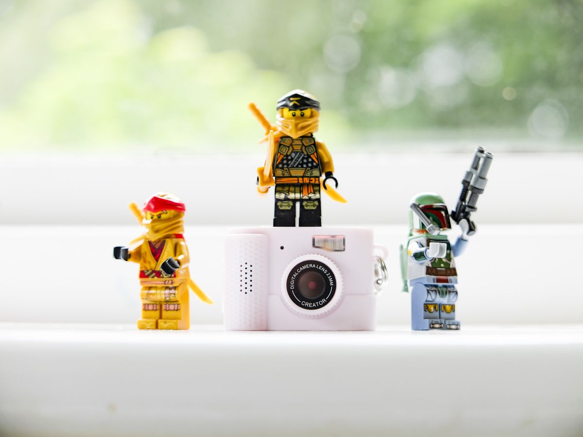 Photo Creator Mini Digital Camera series 3 camera on a white window sill with Lego figures stood besides it