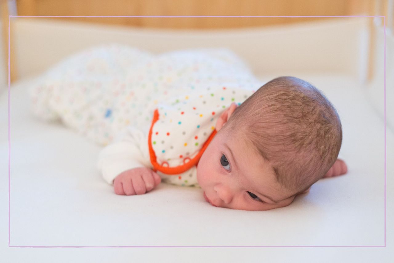 How to dress a baby for sleep illustrated by 3 month old baby lying on her tummy in a sleeping bag in a cot