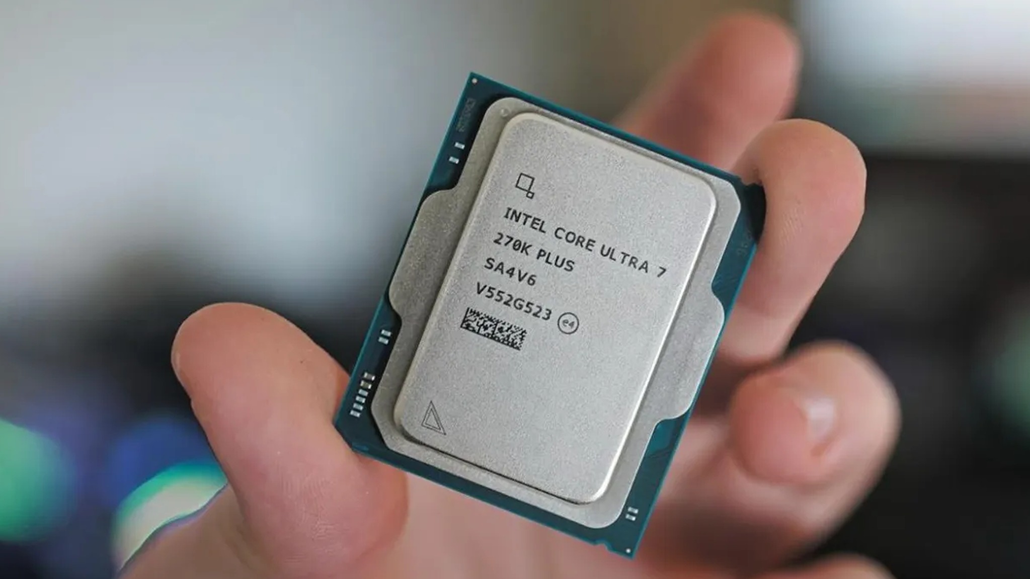 A hand holds an Intel Core Ultra 7 Z78K Plus processor. The silver chip, with text visible, contrasts with a blurred background, suggesting focus and precision.