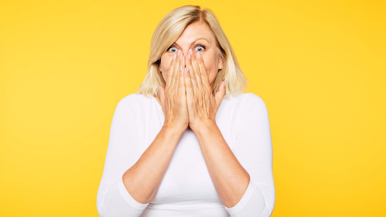 Woman with surprised look on face covering her mouth