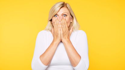 Woman with surprised look on face covering her mouth