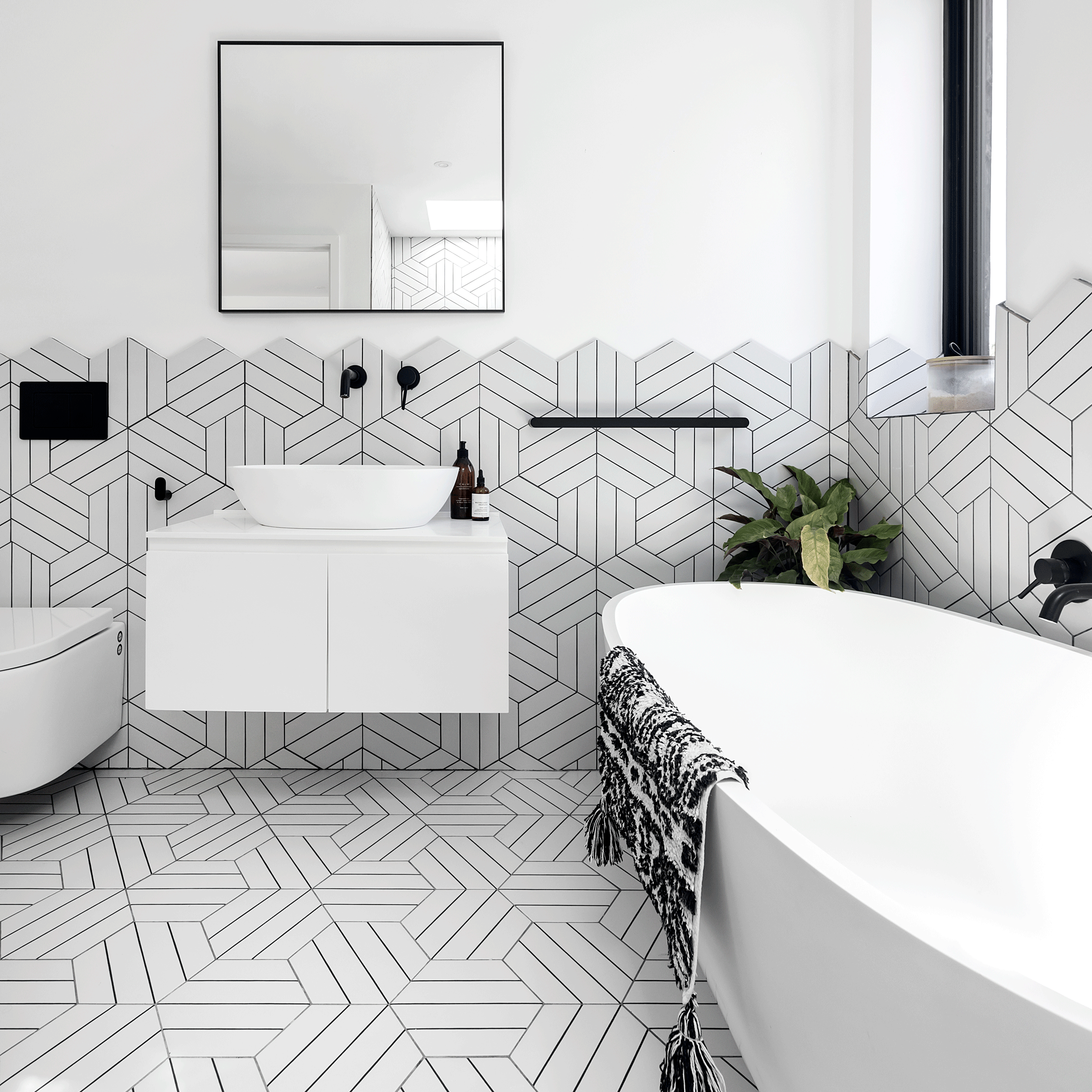 monochrome bathroom with black and white graphic patterned tiles a white modern bath and black fixtures