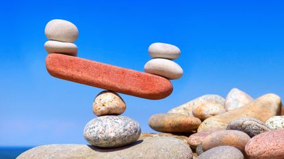 Rocks balance on a teeter-totter, with one end higher than the other.