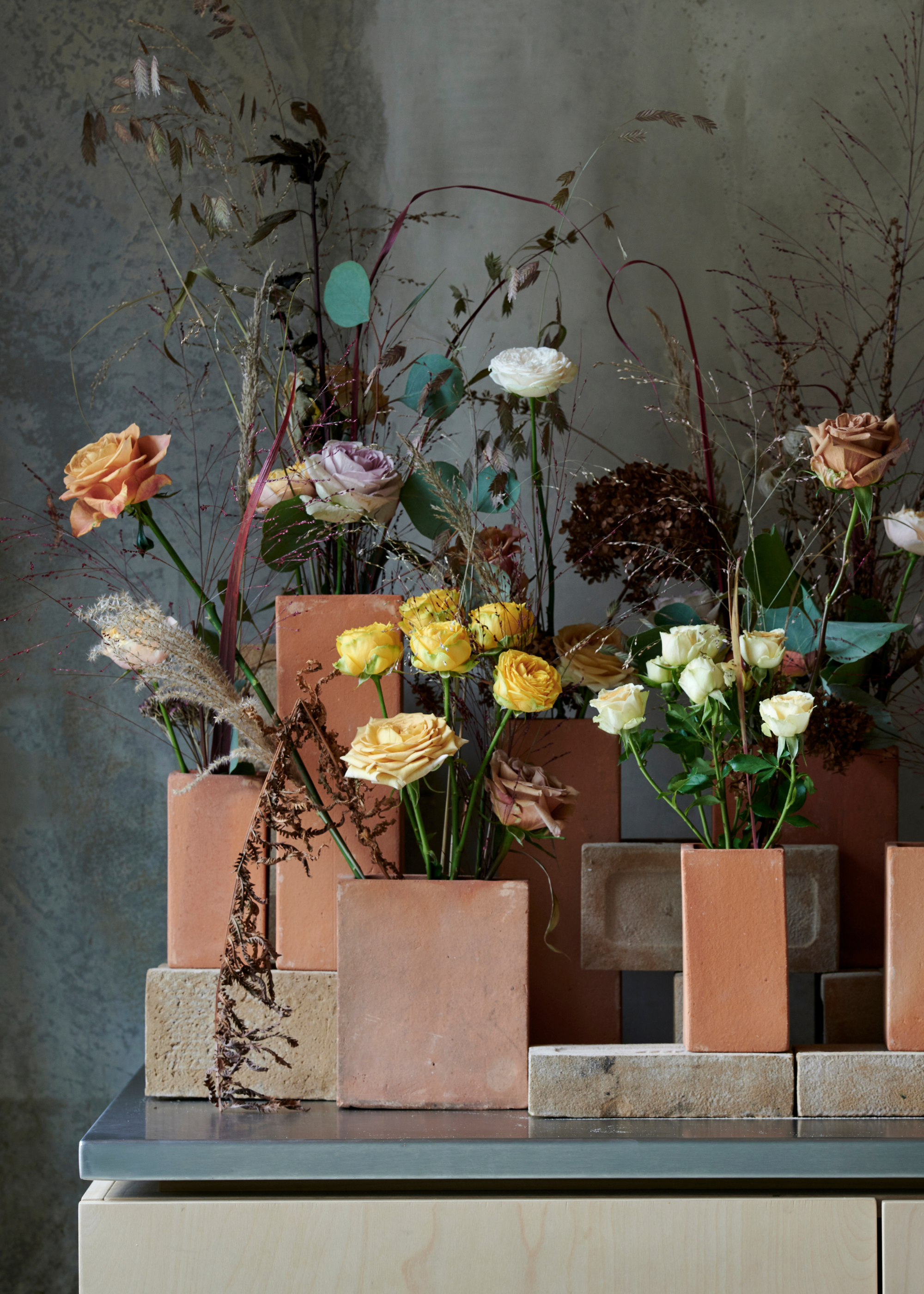A set of cut flowers in rustic block vases, including white roses