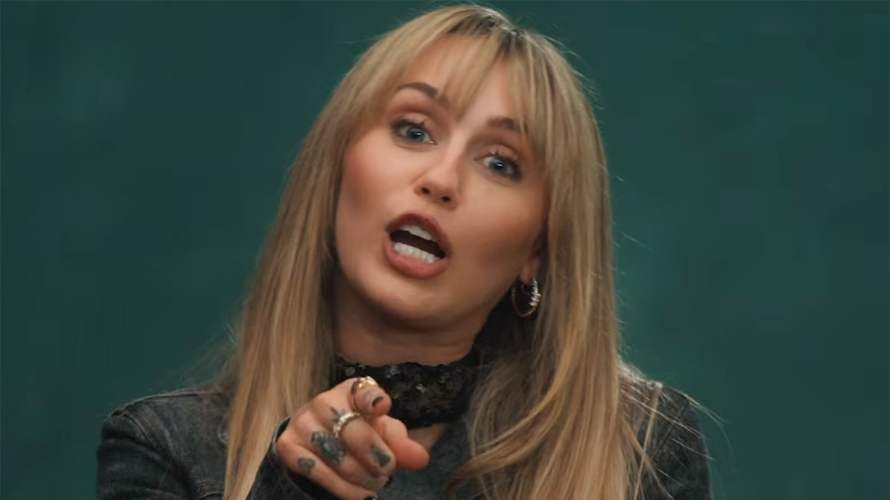 Miley Cyrus interviews as part of the Hannah Montana 20th Anniversary special. She's pointing at the camera.