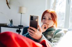 Woman lying on a sofa using a mobile phone