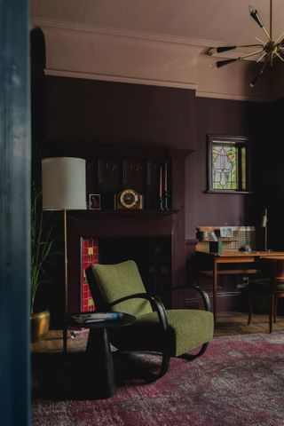 A dark aubergine living room with a contrasting green armchair