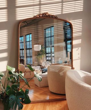 A large gold mirror reflecting a small living room