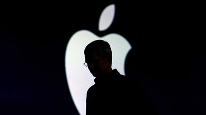 Shadow of Apple CEO Tim Cook standing in front of Apple logo