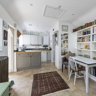 kitchen and dining area with white wall and white dining table and chairs and book shelves and white kitchen units