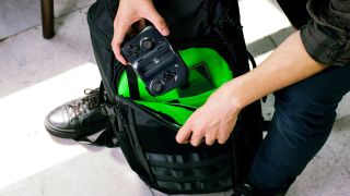 A man kneeling down and putting the Razer Kishi controller into his backpack