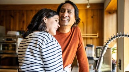 Couple standing together romatically in the kitchen, representing the collapsed doggy sex position