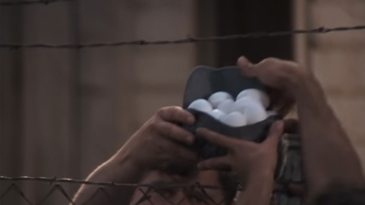 Eggs being handed over a fence in Cool Hand Luke