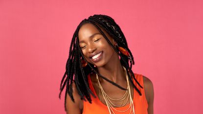 Smiling woman with box braids on a pink backdrop