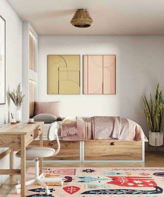Office bedroom with wooden desk, and coordinating bed with built-in storage drawers, and modern artwork in pastel hues on wall.