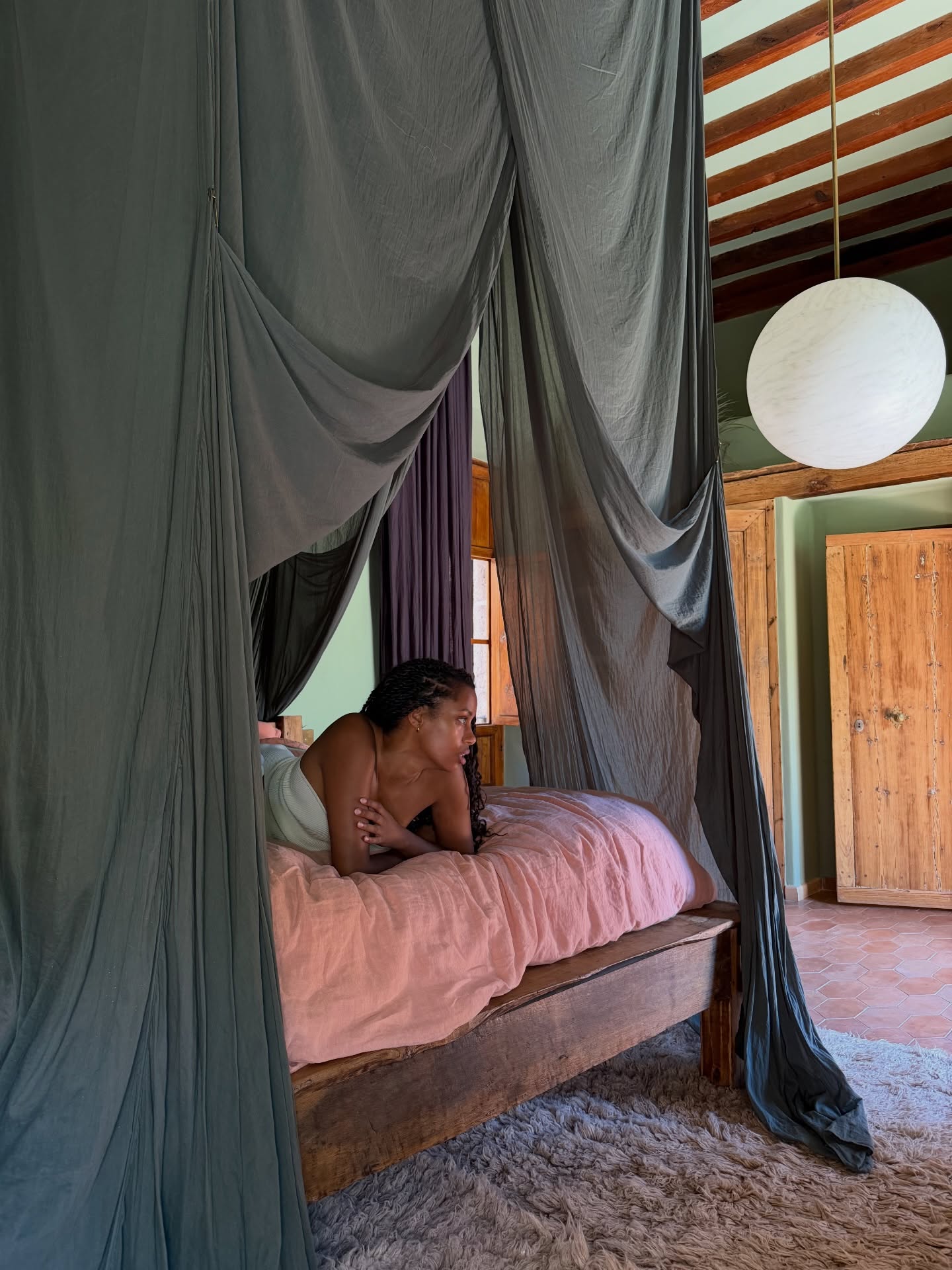 A woman lying on a canopy bed.