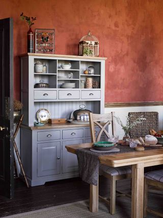 A kitchen with grey dresser and red concrete walls