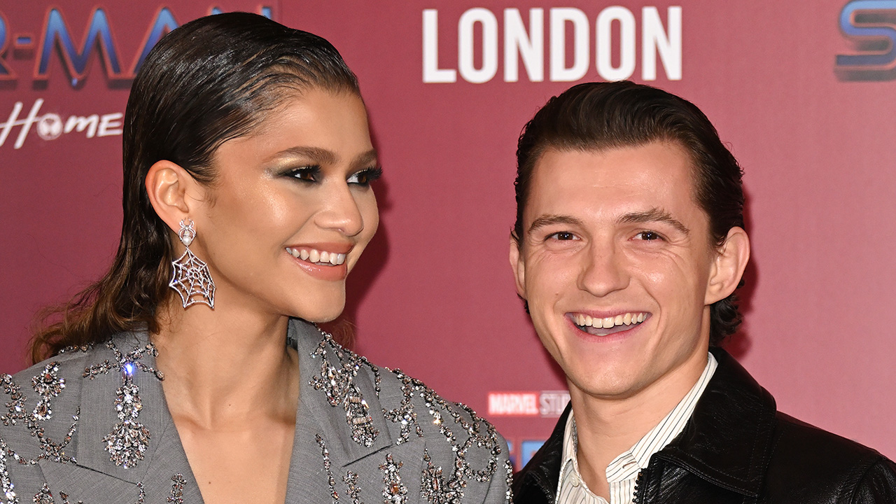 Tom Holland staring at the camera and Zendaya staring into the distance with spider web earrings on at the Spider-Man: No Way Home premiere.