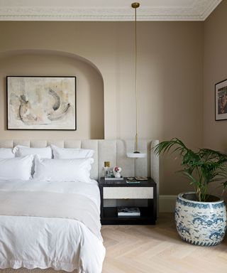 neutral bedroom with oversized, upholstered headboard and white pendant light