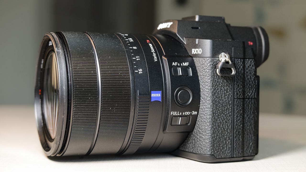 The Sony RX10 V bridge camera on a white table with a patterned wallpaper background