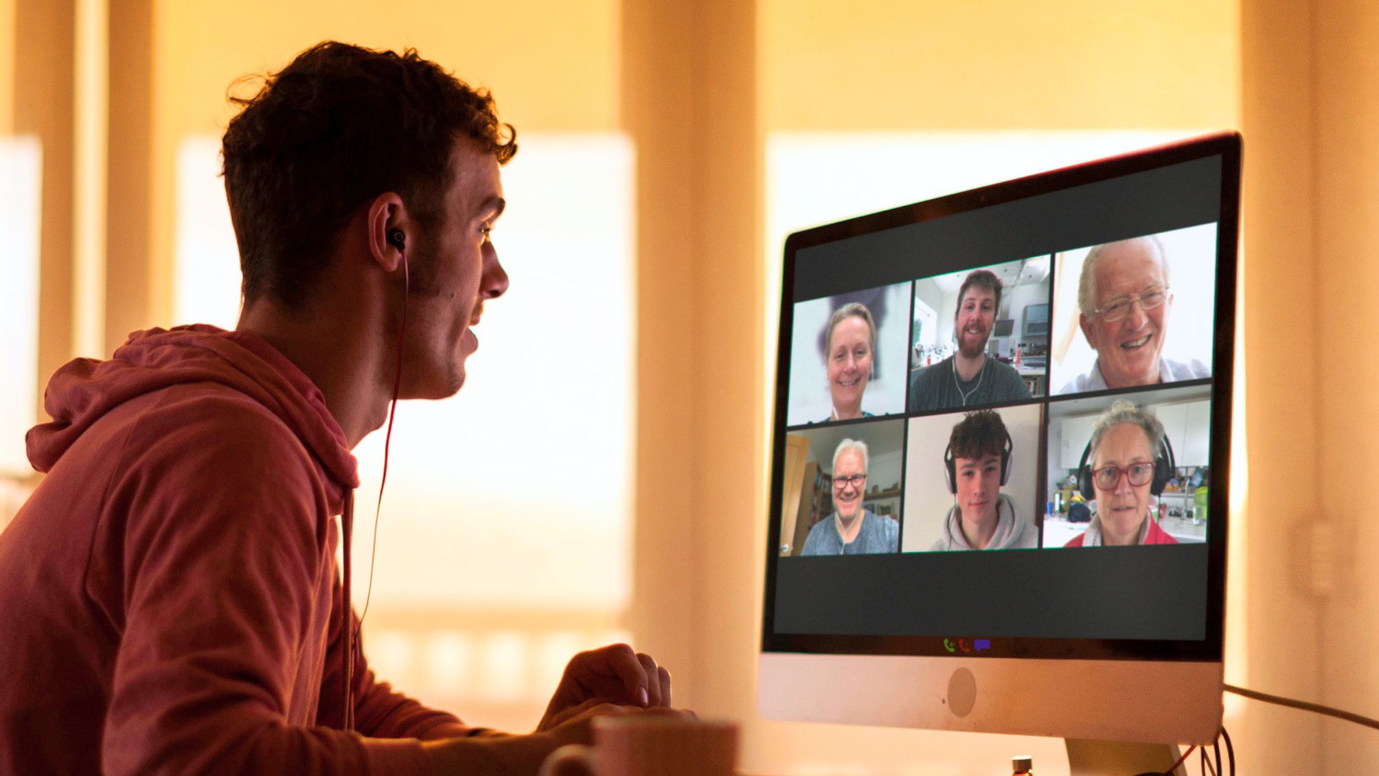 A young man on a Zoom call with his family planning a reunion.