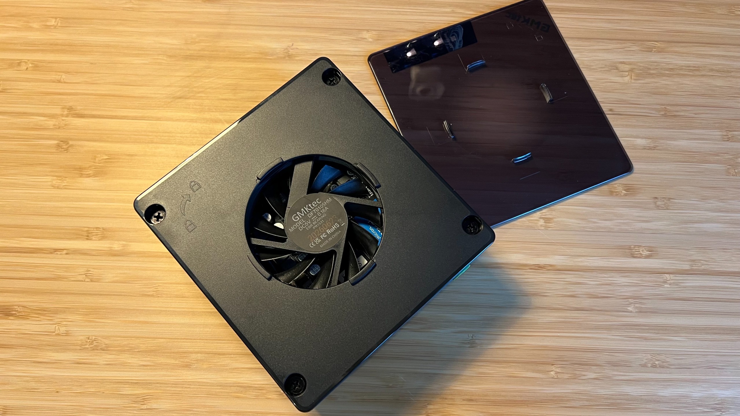 GMKTec K8 Plus mini PC with transparent lid removed, showing screw holes and internal fan