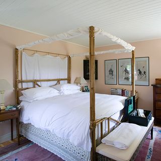 master bedroom with four poster bed and photoframes on wall