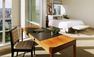 The St Regis guestroom showing white double bed, brown desk and brown chair