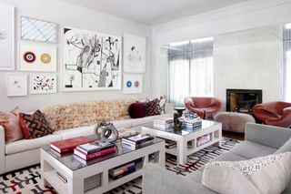 Modern living room with simplistic white and grey walls sofas and fireplace, and patterns and coloured cushions, rugs and chairs