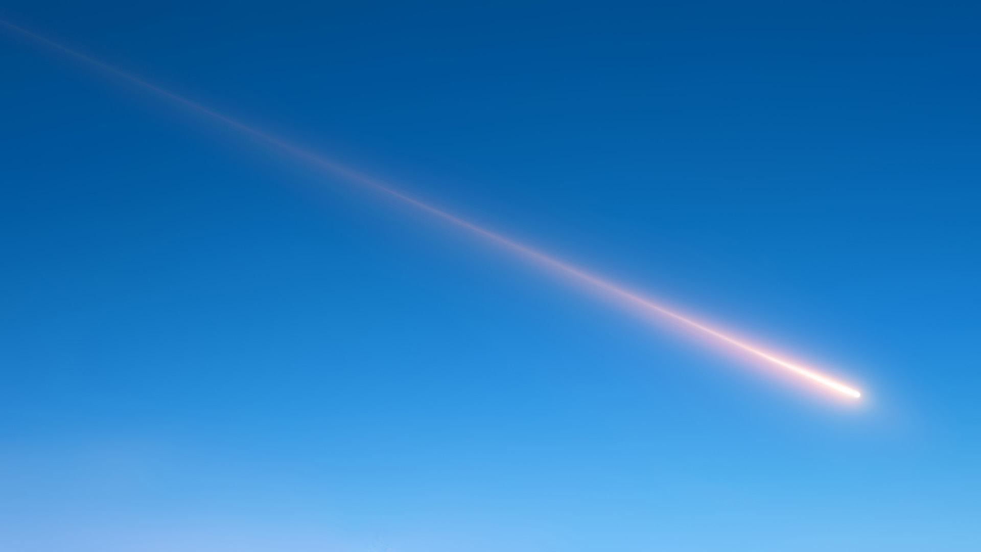 A streak of white moves across the blue sky as a meteor shoots past.