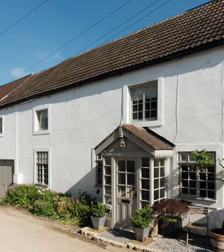 white cottage with small windows and porch