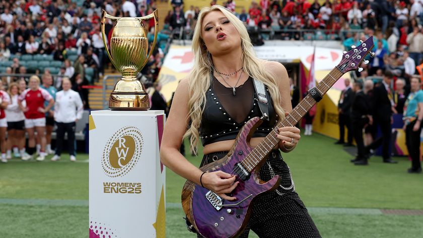 Sophie Lloyd playing guitar next to the Women’s Rugby World Cup trophy in 2025